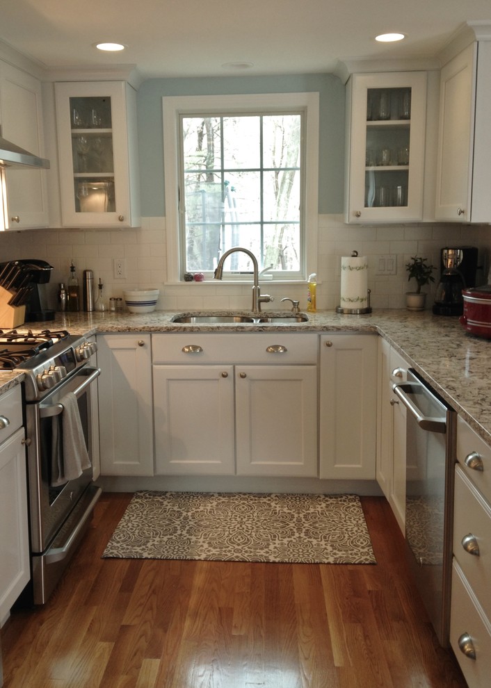 Eat-in kitchen - transitional light wood floor eat-in kitchen idea in Boston with an undermount sink, recessed-panel cabinets, white cabinets, granite countertops, white backsplash, ceramic backsplash, stainless steel appliances and no island