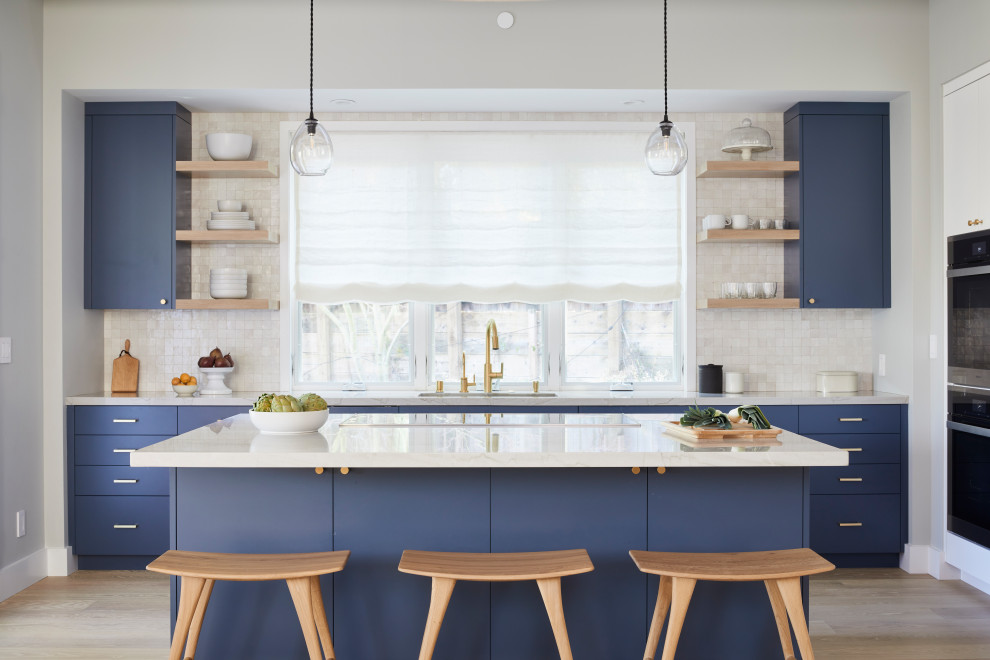 Design ideas for a scandinavian l-shaped kitchen in San Francisco with an undermount sink, flat-panel cabinets, blue cabinets, stainless steel appliances, light hardwood floors, with island, beige floor and white benchtop.
