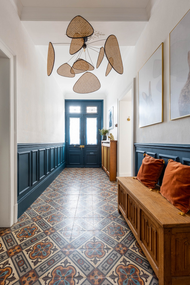 Photo of a mid-sized transitional entry hall in Paris with white walls, multi-coloured floor and a blue front door.