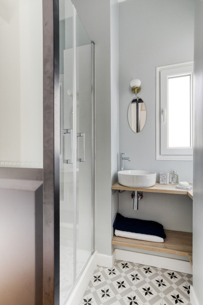 This is an example of a small contemporary 3/4 bathroom in Paris with open cabinets, light wood cabinets, an alcove shower, white tile, subway tile, grey walls, cement tiles, a drop-in sink, wood benchtops, multi-coloured floor, a hinged shower door and brown benchtops.
