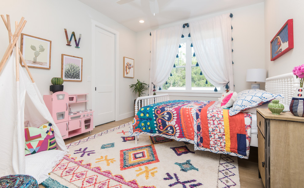 Photo of a beach style kids' bedroom for kids 4-10 years old and girls in Orlando with white walls, medium hardwood floors and brown floor.