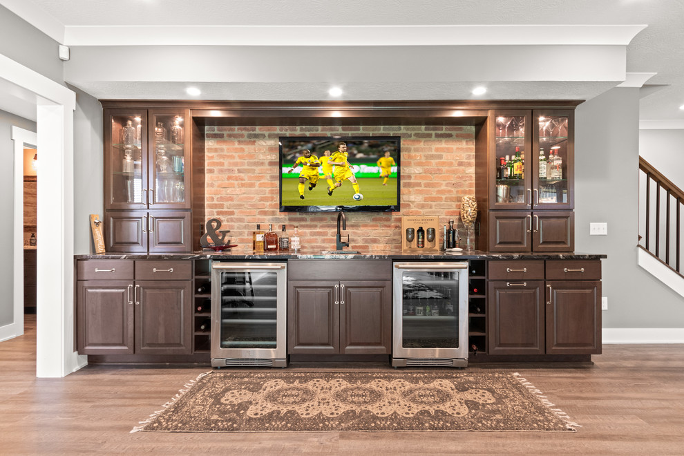 Inspiration for a mid-sized arts and crafts single-wall wet bar in Columbus with an undermount sink, raised-panel cabinets, dark wood cabinets, onyx benchtops, red splashback, brick splashback, vinyl floors, beige floor and black benchtop.