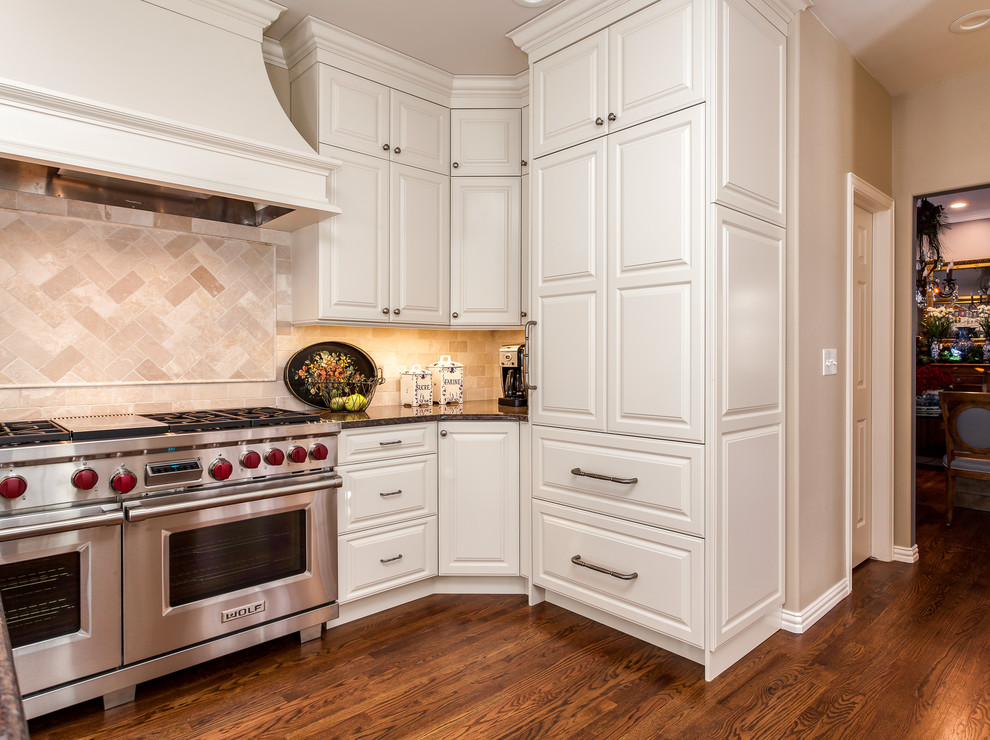 Large traditional l-shaped kitchen pantry in Denver with an undermount sink, raised-panel cabinets, white cabinets, granite benchtops, beige splashback, subway tile splashback, stainless steel appliances, dark hardwood floors and with island.