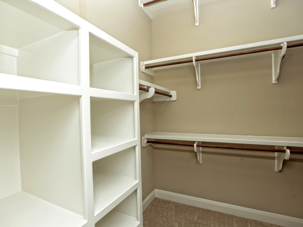 This is an example of a mid-sized country gender-neutral walk-in wardrobe in Austin with open cabinets, white cabinets and carpet.