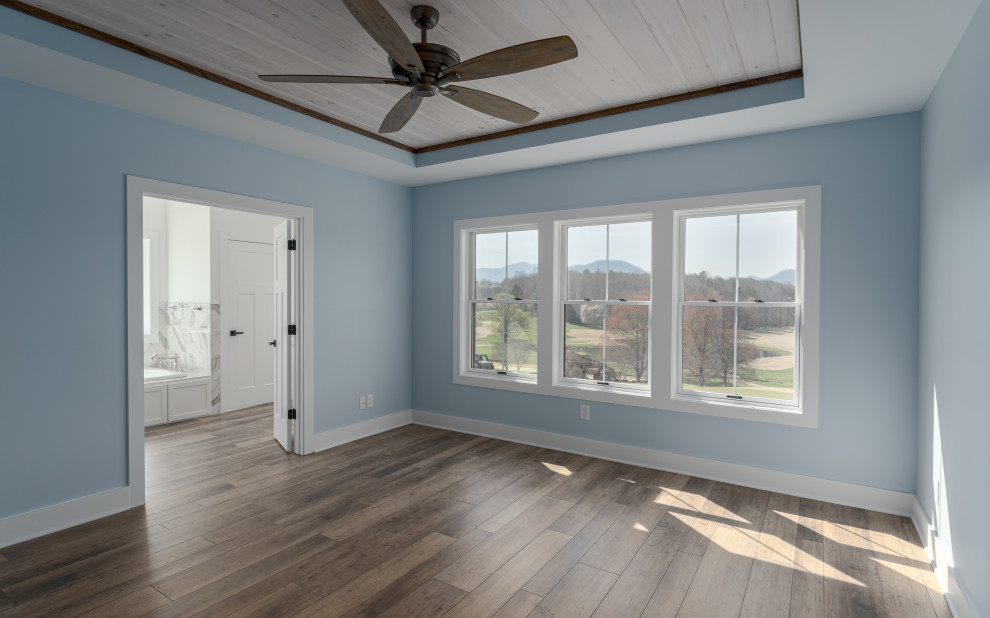 Foto di una camera matrimoniale country di medie dimensioni con pareti blu, pavimento in vinile, pavimento marrone e soffitto ribassato