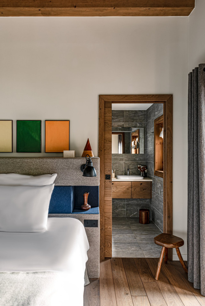 Uriges Schlafzimmer mit weißer Wandfarbe, braunem Holzboden, braunem Boden und freigelegten Dachbalken in Grenoble