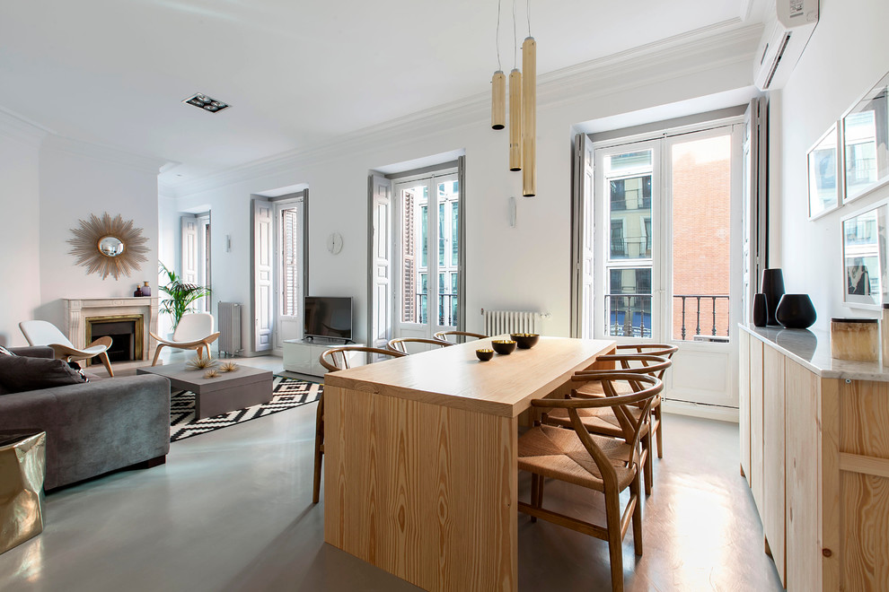Large contemporary open plan dining in Madrid with white walls, concrete floors and a standard fireplace.
