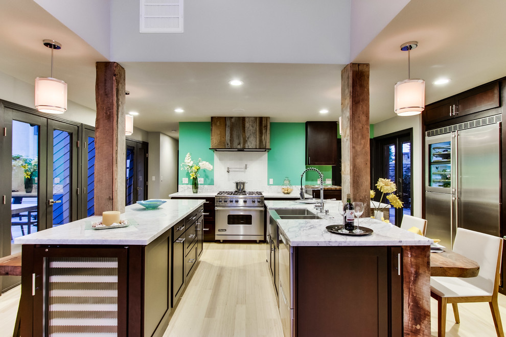 Beach style u-shaped eat-in kitchen in San Diego with a farmhouse sink, recessed-panel cabinets, dark wood cabinets, marble benchtops, green splashback, glass tile splashback and stainless steel appliances.