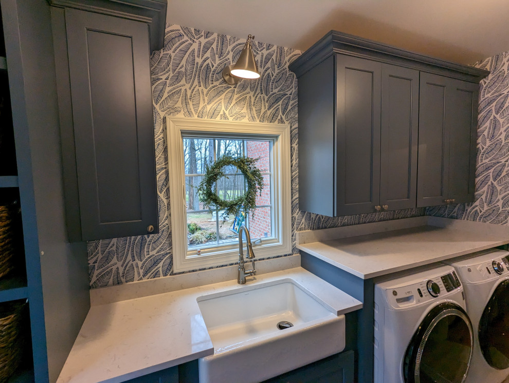 Foto på en mellanstor funkis vita parallell tvättstuga enbart för tvätt, med en rustik diskho, luckor med infälld panel, blå skåp, bänkskiva i kvarts, blå väggar, en tvättmaskin och torktumlare bredvid varandra och grått golv