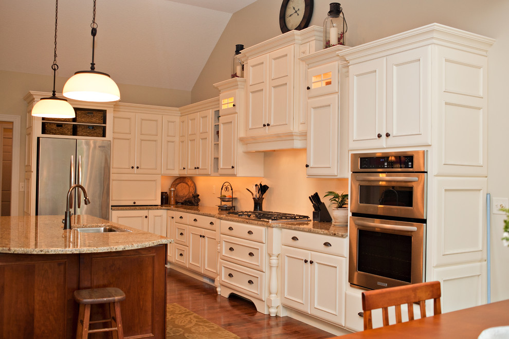 This is an example of a traditional l-shaped eat-in kitchen in Chicago with an undermount sink, white cabinets, granite benchtops and stainless steel appliances.