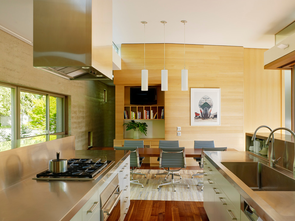 Photo of a mid-sized modern galley eat-in kitchen in San Francisco with stainless steel appliances, stainless steel benchtops, an integrated sink, flat-panel cabinets, white cabinets, metallic splashback and light hardwood floors.