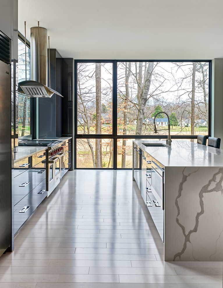 Example of a trendy galley white floor kitchen design with an undermount sink, flat-panel cabinets, gray cabinets, window backsplash, stainless steel appliances, an island and white countertops