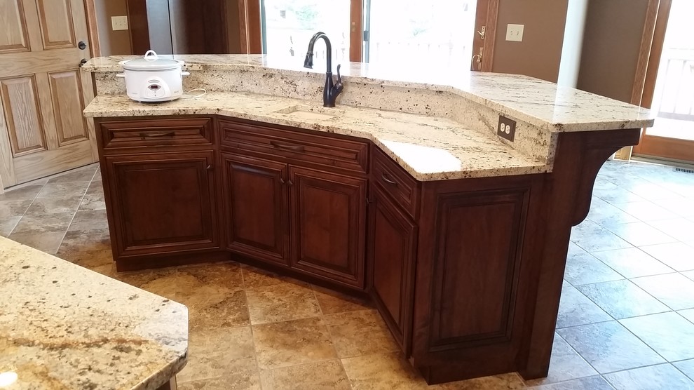 Example of a large classic u-shaped ceramic tile kitchen design with raised-panel cabinets, medium tone wood cabinets, granite countertops, stainless steel appliances, two islands and a farmhouse sink