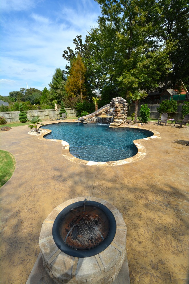 This is an example of a mid-sized country backyard custom-shaped lap pool in Little Rock with a water slide and natural stone pavers.