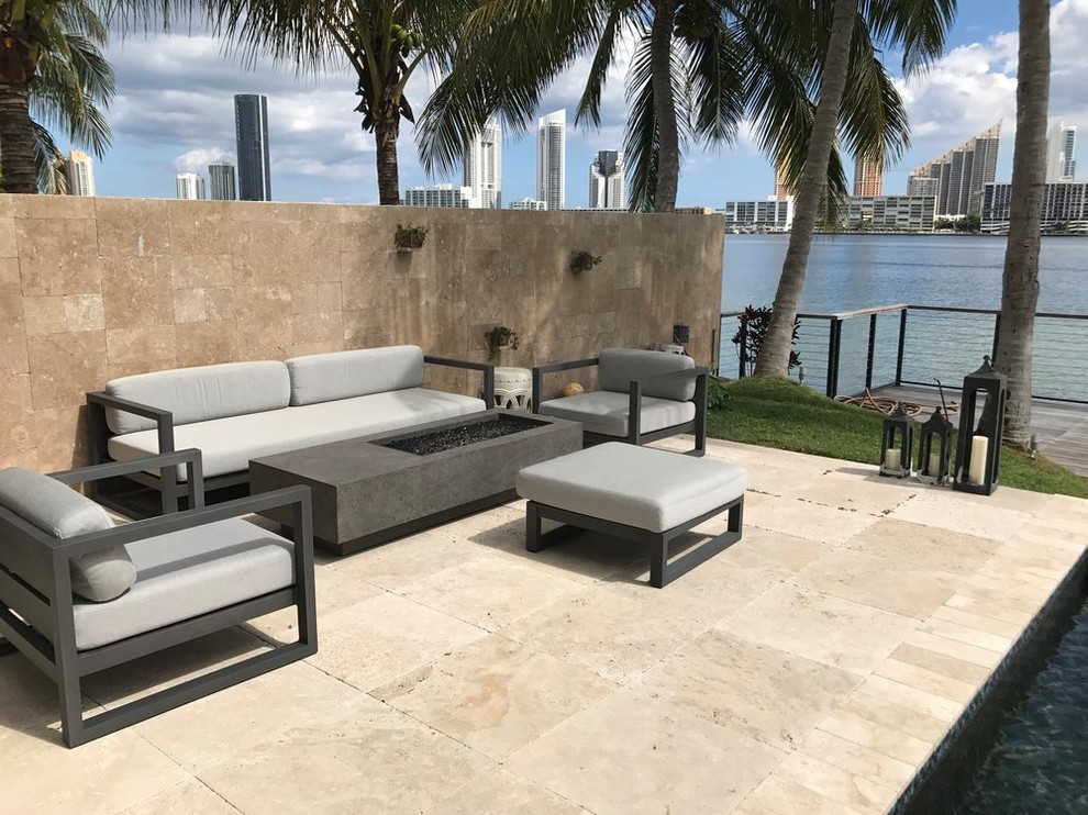 This is an example of a mid-sized modern backyard patio in Miami with a fire feature, tile and no cover.