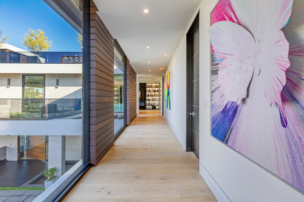 На фото: огромный коридор в стиле модернизм с белыми стенами, бежевым полом и многоуровневым потолком с