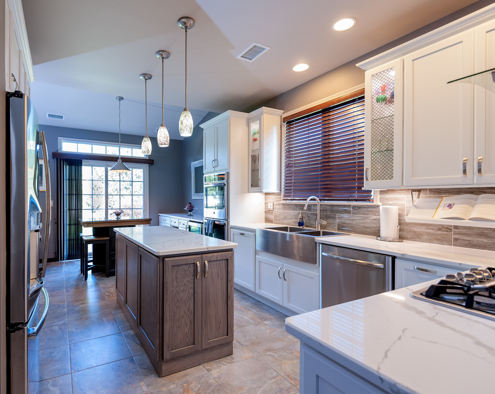 Enclosed kitchen - mid-sized transitional l-shaped porcelain tile and multicolored floor enclosed kitchen idea in Philadelphia with a farmhouse sink, shaker cabinets, white cabinets, quartzite countertops, brown backsplash, stone tile backsplash, stainless steel appliances, an island and white countertops