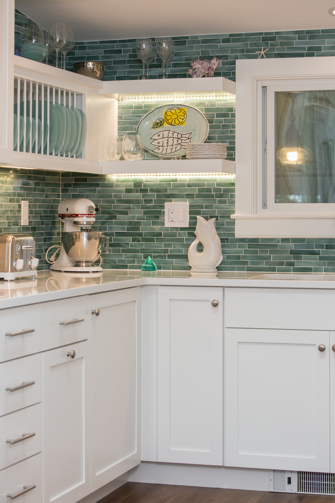 Photo of a small beach style u-shaped separate kitchen in Boston with an undermount sink, shaker cabinets, white cabinets, quartz benchtops, green splashback, subway tile splashback, stainless steel appliances, medium hardwood floors, no island and white benchtop.