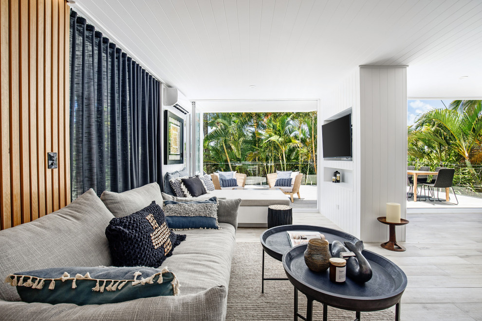 Mid-sized beach style open concept living room in Sunshine Coast with white walls, porcelain floors, a wall-mounted tv and grey floor.