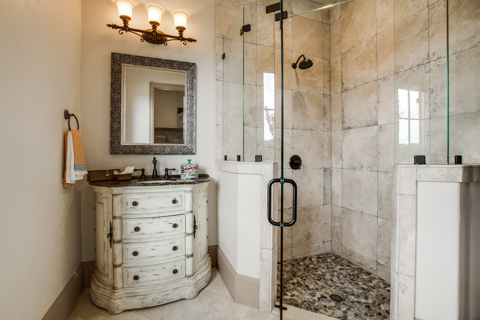 Design ideas for a mid-sized mediterranean bathroom in Dallas with an undermount sink, furniture-like cabinets, dark wood cabinets, granite benchtops, a corner shower, a one-piece toilet, beige tile, porcelain tile, beige walls and porcelain floors.