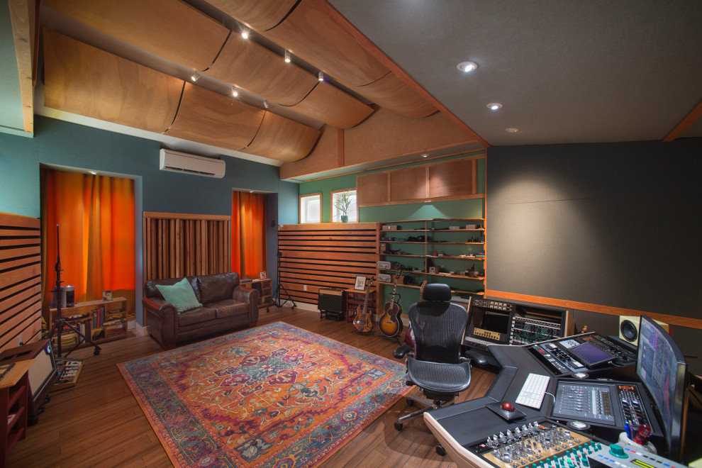 This is an example of a contemporary home studio in Portland Maine with multi-coloured walls, medium hardwood floors, a built-in desk, brown floor, vaulted and wood.