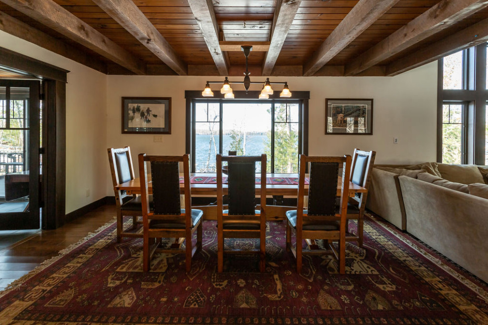 Mid-sized open plan dining in Other with white walls, medium hardwood floors, a standard fireplace, a stone fireplace surround, brown floor, exposed beam and decorative wall panelling.
