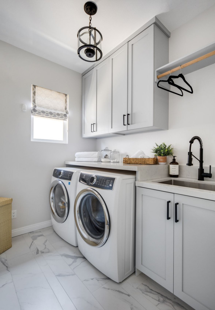 Inspiration for a mid-sized transitional single-wall dedicated laundry room in Orange County with an undermount sink, shaker cabinets, grey cabinets, quartz benchtops, grey walls, porcelain floors, a side-by-side washer and dryer, white floor and white benchtop.