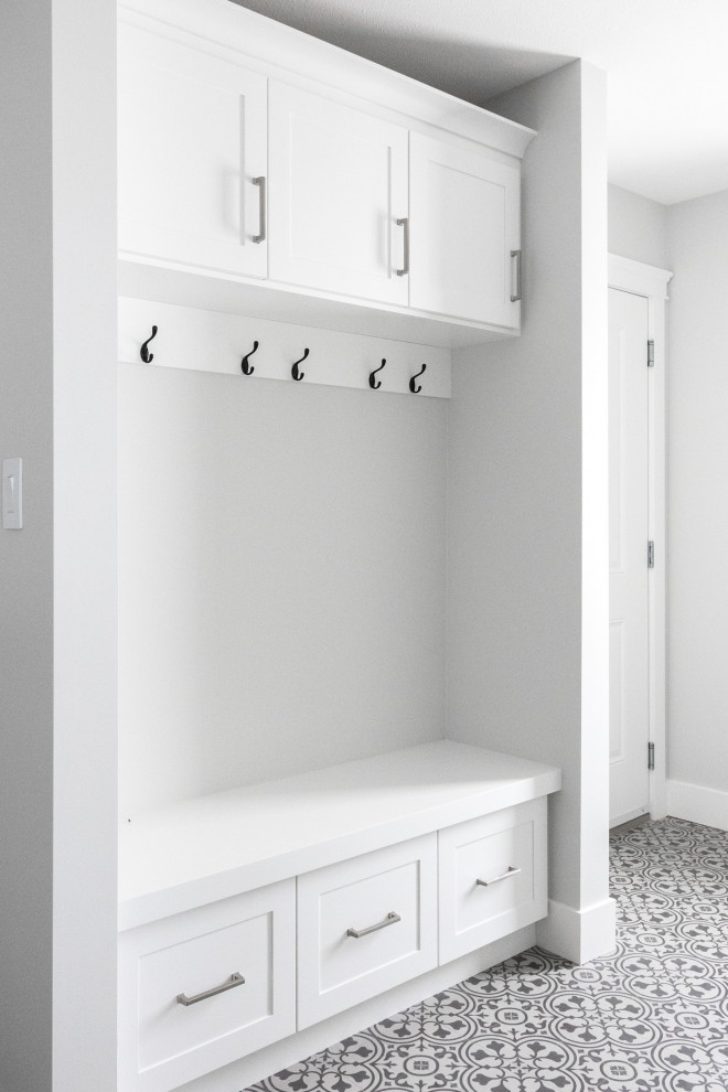 Design ideas for a mid-sized country single-wall dedicated laundry room in Other with shaker cabinets, white cabinets, white walls, a side-by-side washer and dryer and multi-coloured floor.