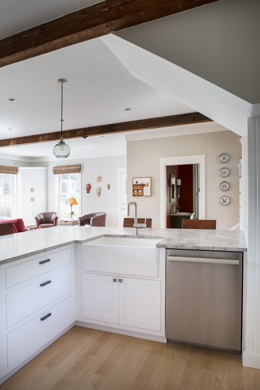 Inspiration for a large transitional u-shaped light wood floor eat-in kitchen remodel in Boston with a farmhouse sink, shaker cabinets, white cabinets, granite countertops, gray backsplash, porcelain backsplash, stainless steel appliances and an island