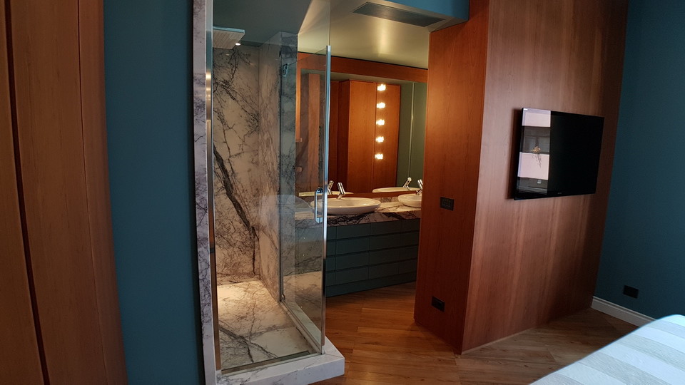 Photo of a mid-sized eclectic master wet room bathroom in Rome with turquoise cabinets, a wall-mount toilet, blue walls, medium hardwood floors, a vessel sink, marble benchtops, brown floor, a hinged shower door, grey benchtops and beaded inset cabinets.