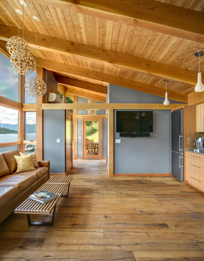 Photo of a mid-sized country formal open concept living room in Seattle with grey walls, medium hardwood floors, no fireplace, a wall-mounted tv and brown floor.