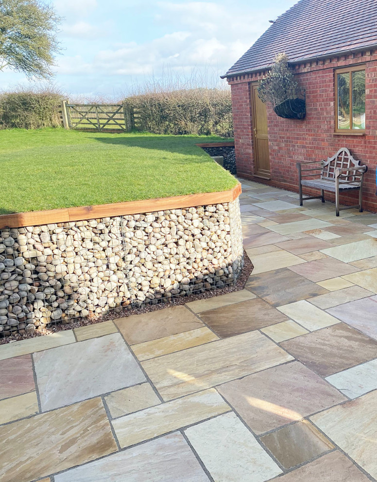 Photo of a large country patio in Essex with natural stone pavers.