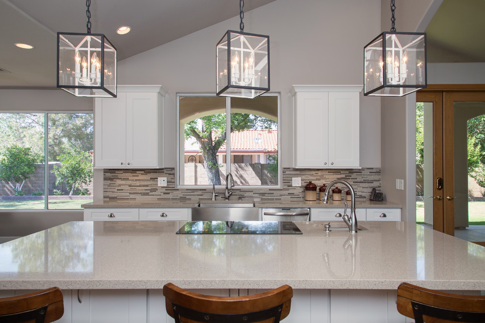 This is an example of a large transitional u-shaped eat-in kitchen in Phoenix with a farmhouse sink, shaker cabinets, white cabinets, quartz benchtops, beige splashback, glass sheet splashback, stainless steel appliances, dark hardwood floors, with island, brown floor and beige benchtop.