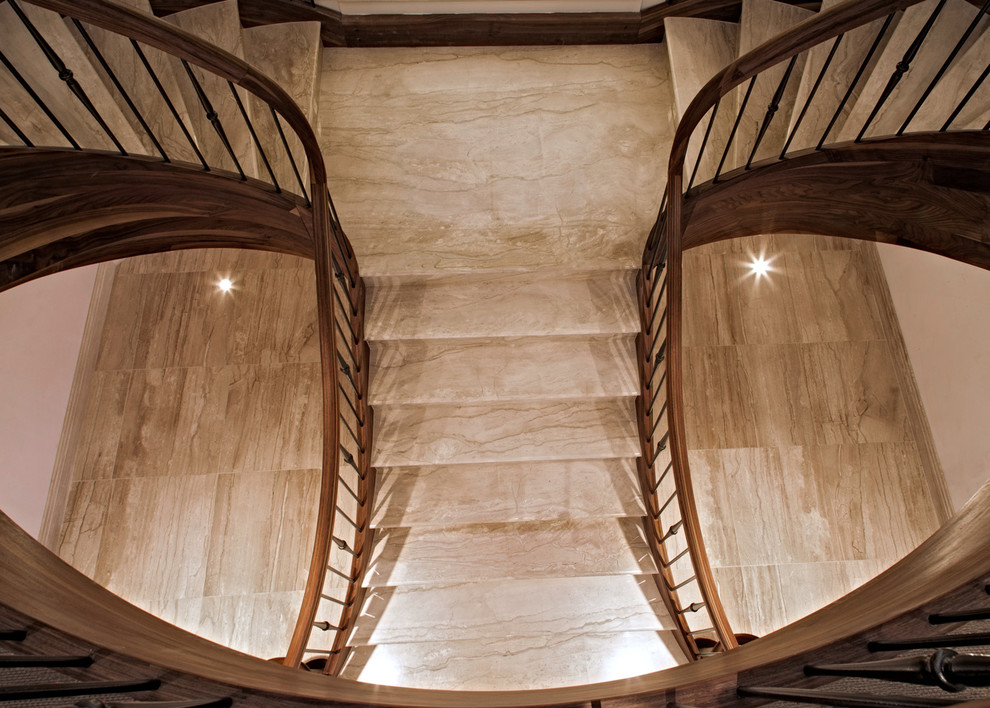 Idée de décoration pour un grand escalier courbe tradition en marbre avec des contremarches en bois et un garde-corps en matériaux mixtes.