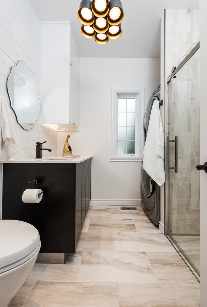 Inspiration for a mid-sized contemporary 3/4 bathroom in Montreal with flat-panel cabinets, dark wood cabinets, a curbless shower, a wall-mount toilet, beige tile, white walls, porcelain floors, an undermount sink, solid surface benchtops, a sliding shower screen and a laundry.