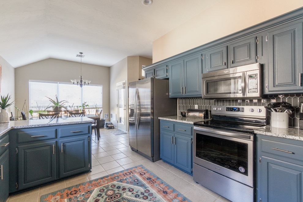 This is an example of a mid-sized traditional l-shaped eat-in kitchen in Oklahoma City with raised-panel cabinets, blue cabinets, granite benchtops, grey splashback, glass tile splashback, no island and grey benchtop.