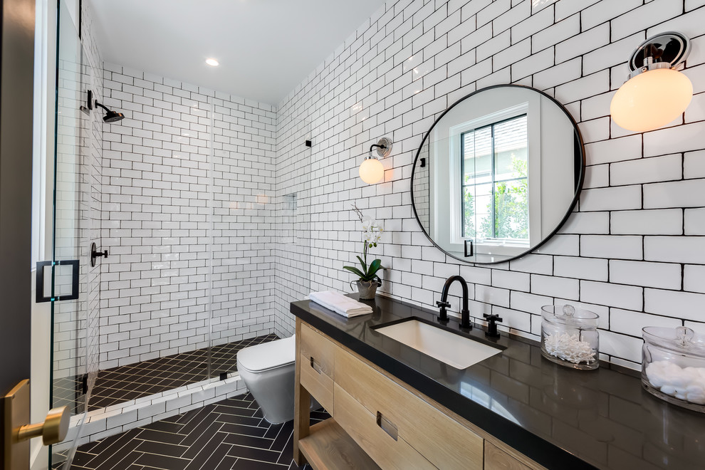 Example of a transitional 3/4 white tile and subway tile black floor alcove shower design in Los Angeles with flat-panel cabinets, light wood cabinets, an undermount sink, a hinged shower door and black countertops