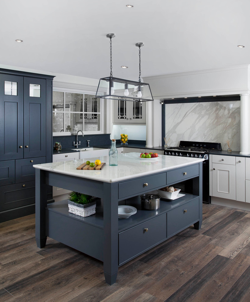 Photo of a mid-sized transitional l-shaped eat-in kitchen in Other with a farmhouse sink, beaded inset cabinets, grey cabinets, marble benchtops, grey splashback, marble splashback, black appliances, medium hardwood floors and with island.