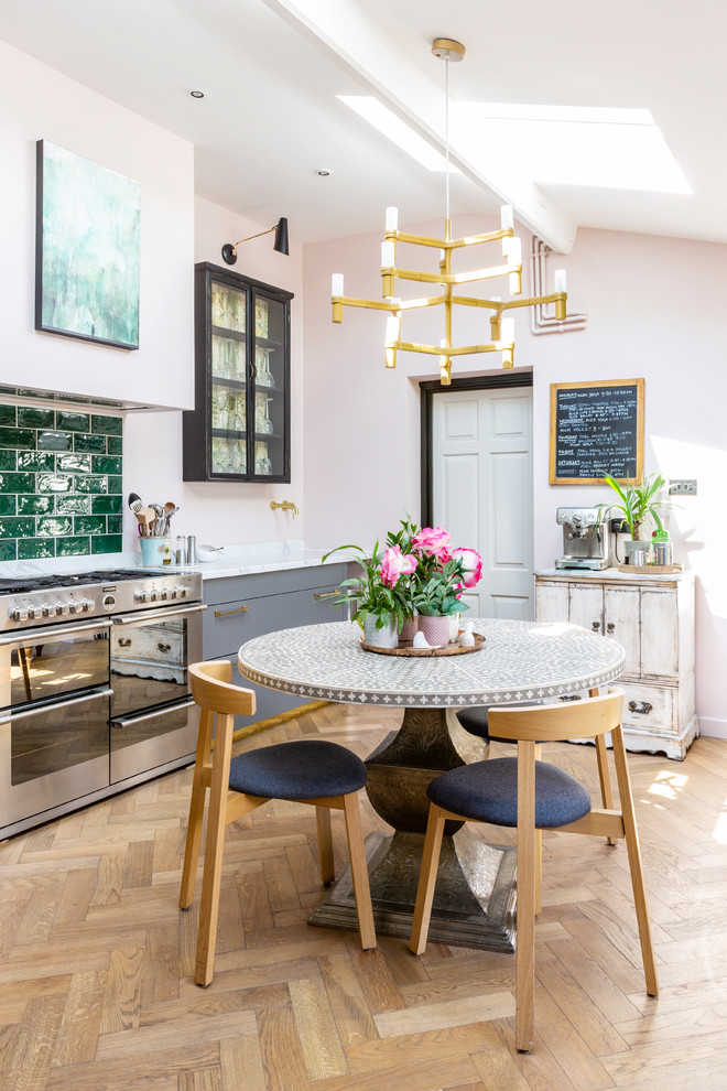Inspiration for an eclectic single-wall eat-in kitchen in Gloucestershire with flat-panel cabinets, grey cabinets, marble benchtops, green splashback, subway tile splashback, stainless steel appliances, light hardwood floors, no island, beige floor and white benchtop.