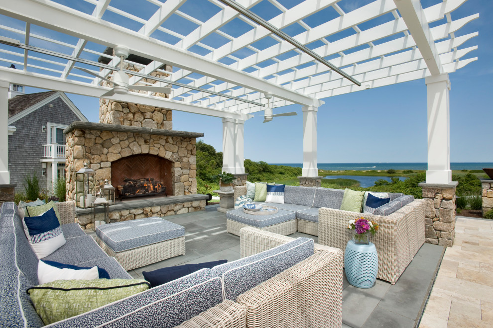 Large beach style backyard patio in Boston with with fireplace, a pergola and tile.