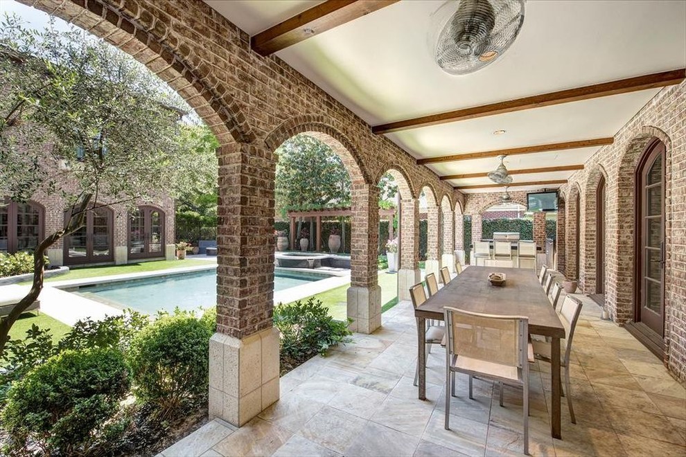 This is an example of a large mediterranean courtyard patio in Houston with an outdoor kitchen, stamped concrete and a roof extension.