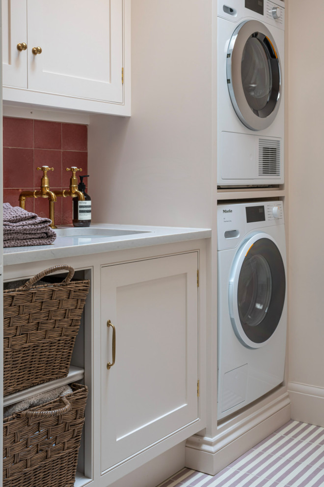 Transitional laundry room in Buckinghamshire with shaker cabinets, solid surface benchtops, pink splashback, ceramic splashback, ceramic floors, pink floor, white benchtop and an undermount sink.