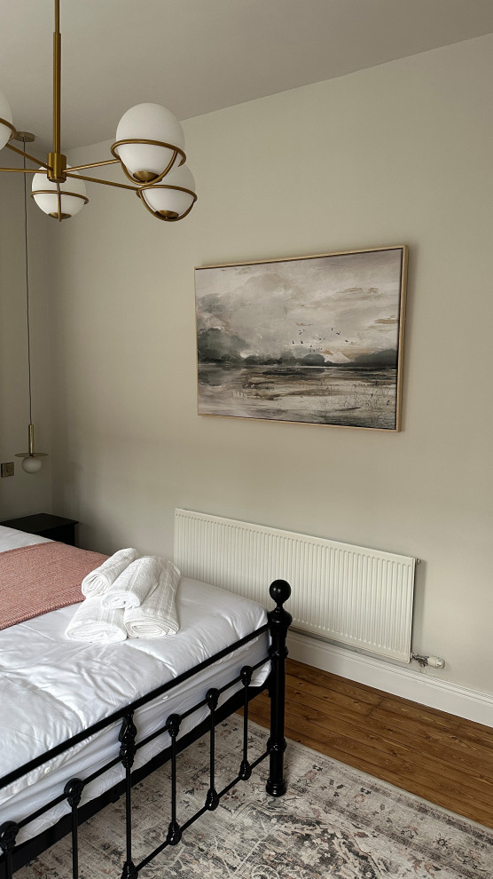 Foto de habitación de invitados retro grande sin chimenea con paredes blancas, suelo de madera en tonos medios y suelo marrón