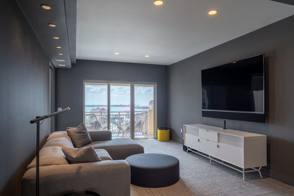 Ejemplo de sala de estar tipo loft moderna de tamaño medio con paredes grises, moqueta, televisor colgado en la pared, suelo gris y bandeja