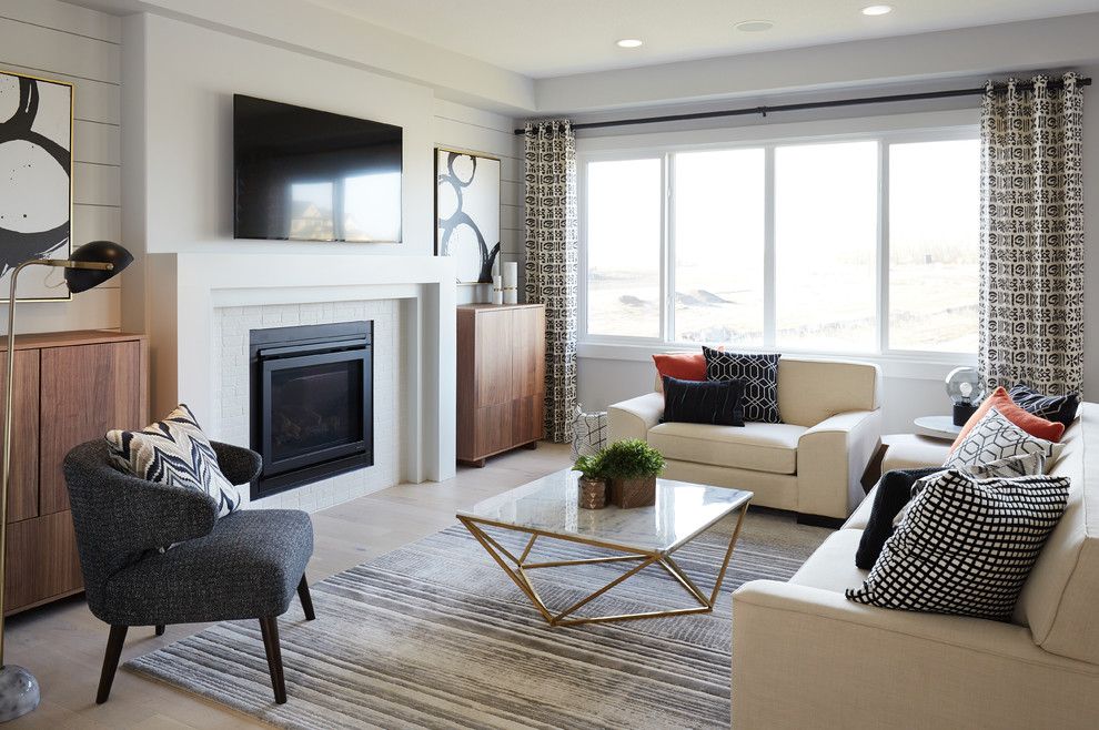 Mid-sized transitional open concept living room in Edmonton with white walls, light hardwood floors, a standard fireplace, a wall-mounted tv and beige floor.