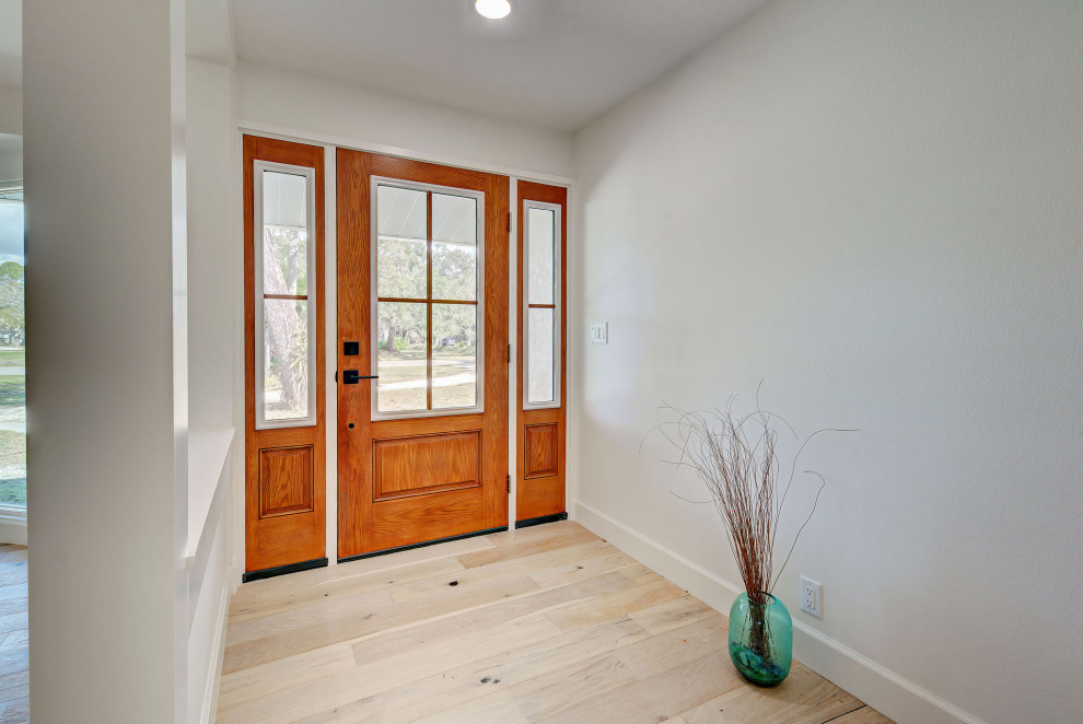 Immagine di una porta d'ingresso minimal con parquet chiaro, una porta singola e una porta in legno bruno