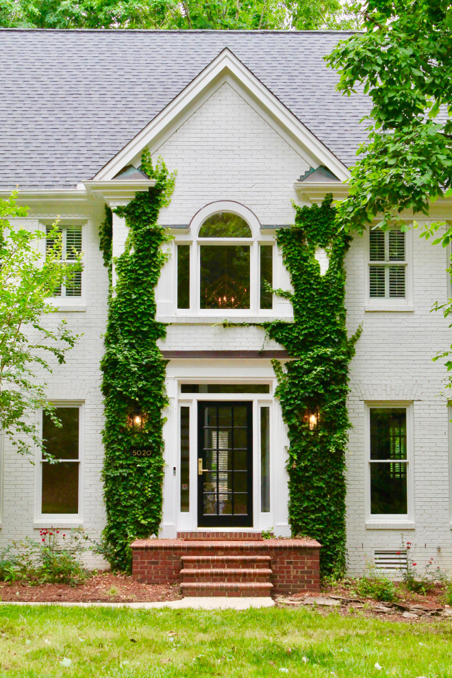 Mid-sized transitional three-storey brick white house exterior in Raleigh with a shingle roof and a black roof.