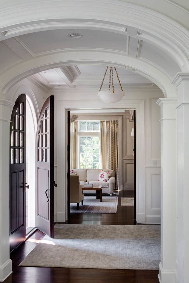 Photo of an expansive traditional foyer in Boston with white walls, dark hardwood floors, a double front door and a brown front door.