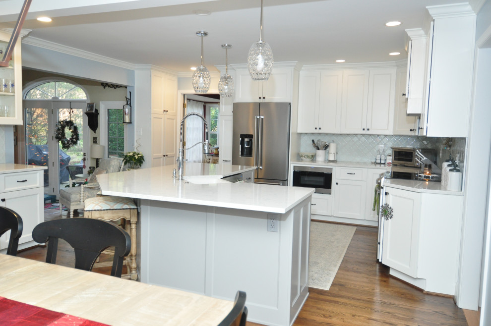 This is an example of a large transitional l-shaped eat-in kitchen in DC Metro with a farmhouse sink, white cabinets, quartz benchtops, glass tile splashback and with island.
