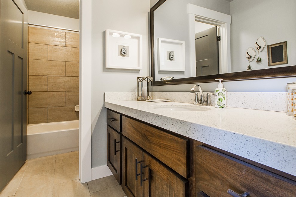Photo of a mid-sized arts and crafts kids bathroom in Salt Lake City with flat-panel cabinets, medium wood cabinets, a drop-in tub, a shower/bathtub combo, a two-piece toilet, beige tile, ceramic tile, grey walls, ceramic floors, an undermount sink and granite benchtops.